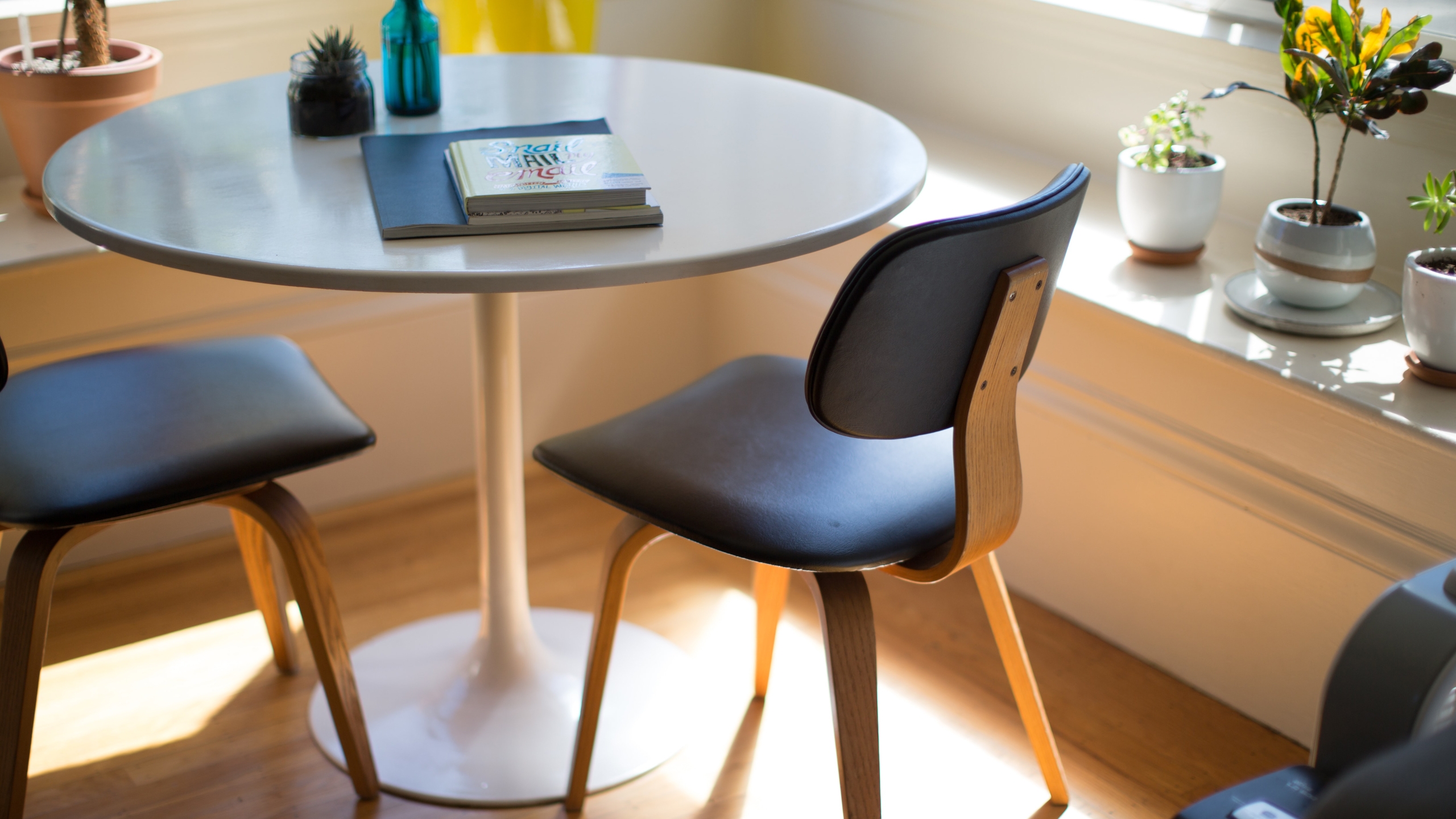 Dining room with bench seats, round table, modern dining table, and potted plants.